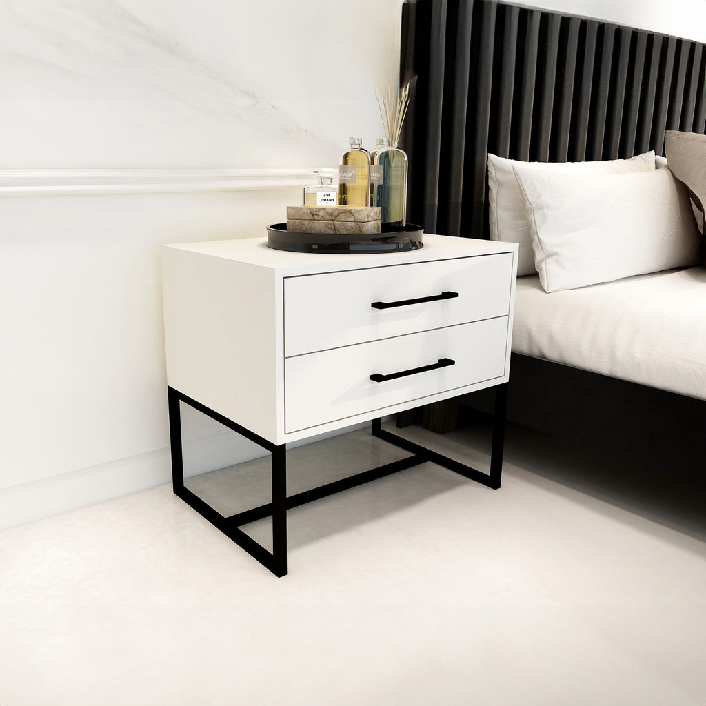 White nightstand with black legs next to a bed in a bedroom setting